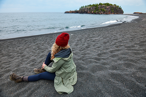 Woman sitting on black sand beach